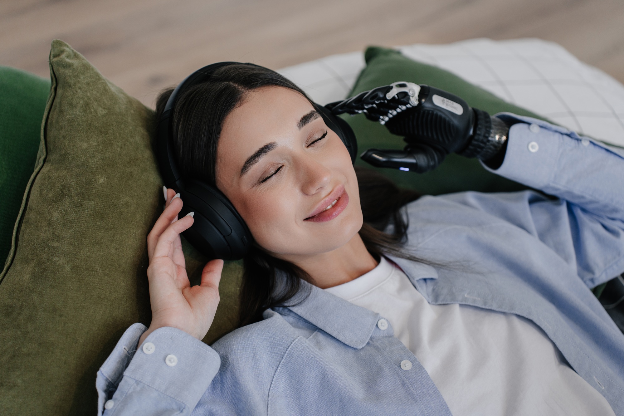 girl is lying on the bed listening music by headphones, holds headphones with bionic artificial arm